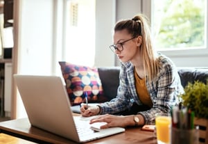 Une femme blonde travaillant sur un ordinateur qui prend des note au sujet de l'article : 