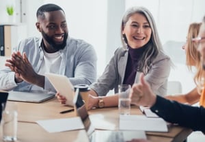 Quatre collègues de travail heureux de connaitre les 6 avantages du vote électronique.